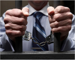 A closeup shot of a man handcuffed in a jail