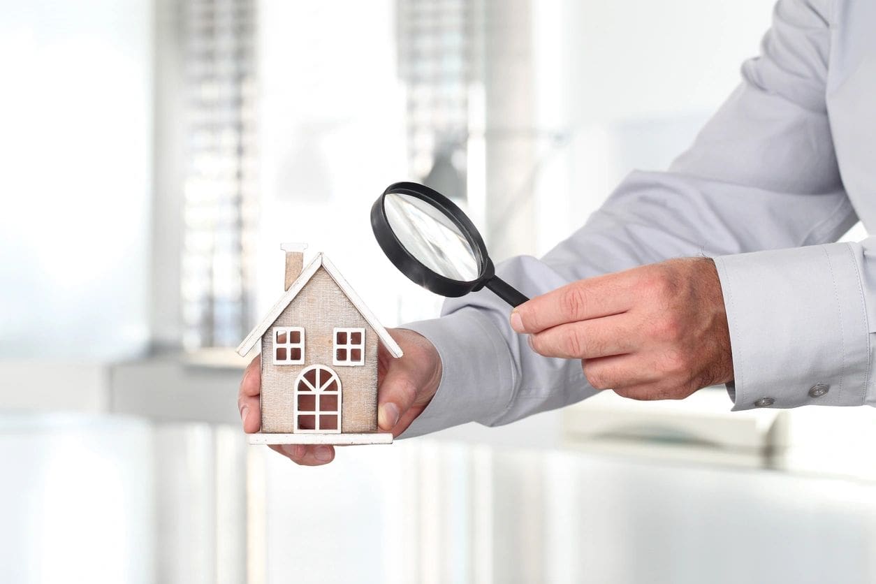 A person holding a house and magnifying glass