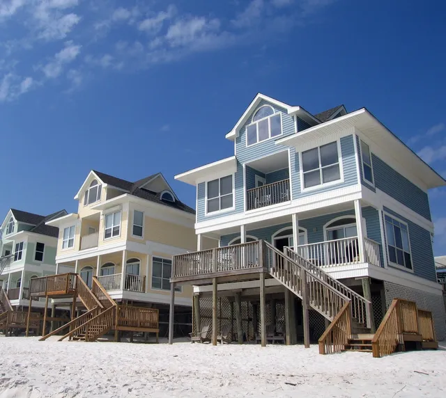 A beach front home with stairs going up to it.